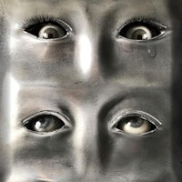 a metal sculpture with three eyes on it